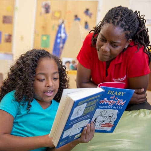 teacher at a daycare hiring near me reading with a student